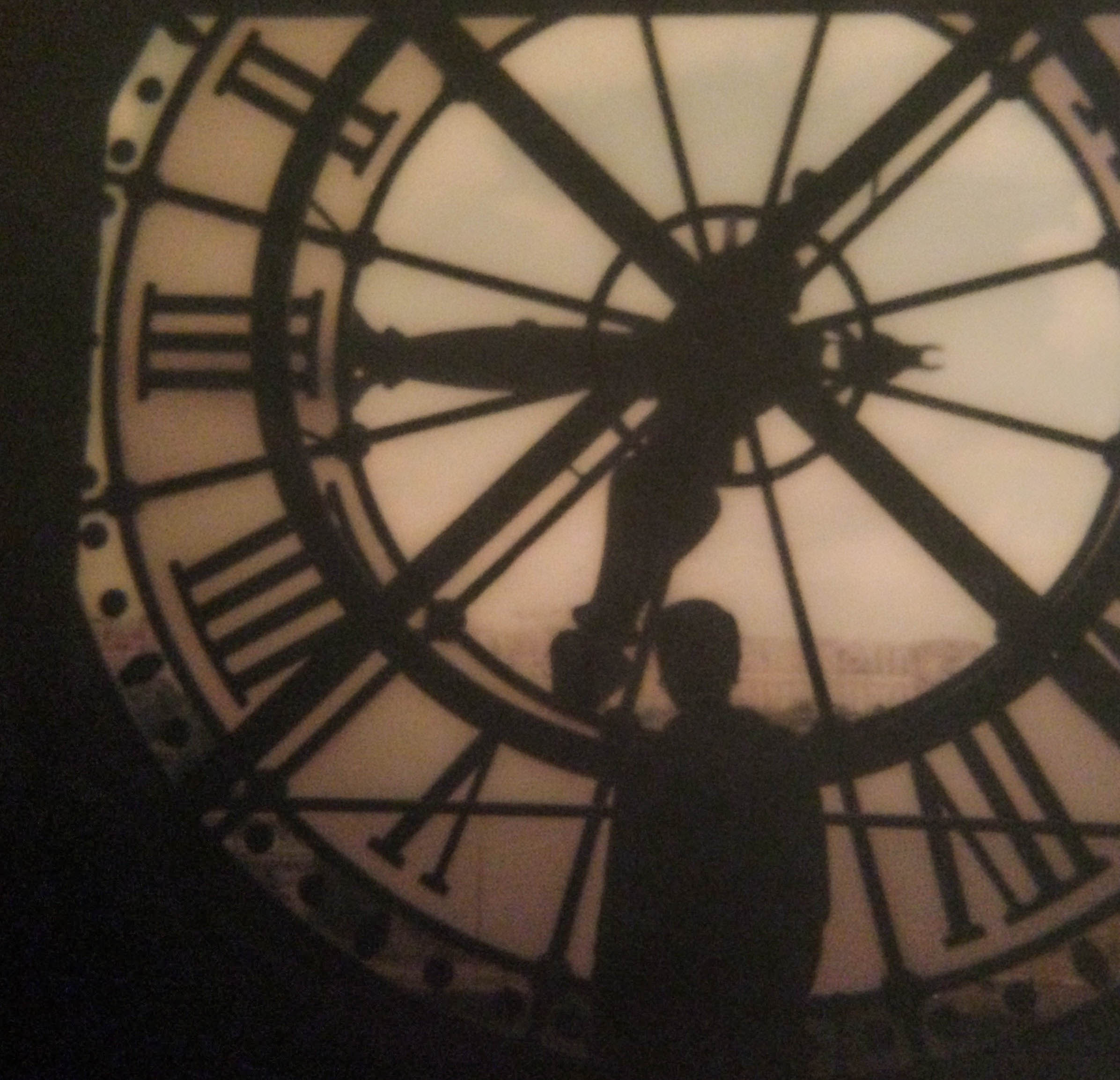A silhouette of a person standing in front of the clock tower within the Musée d’Orsay.