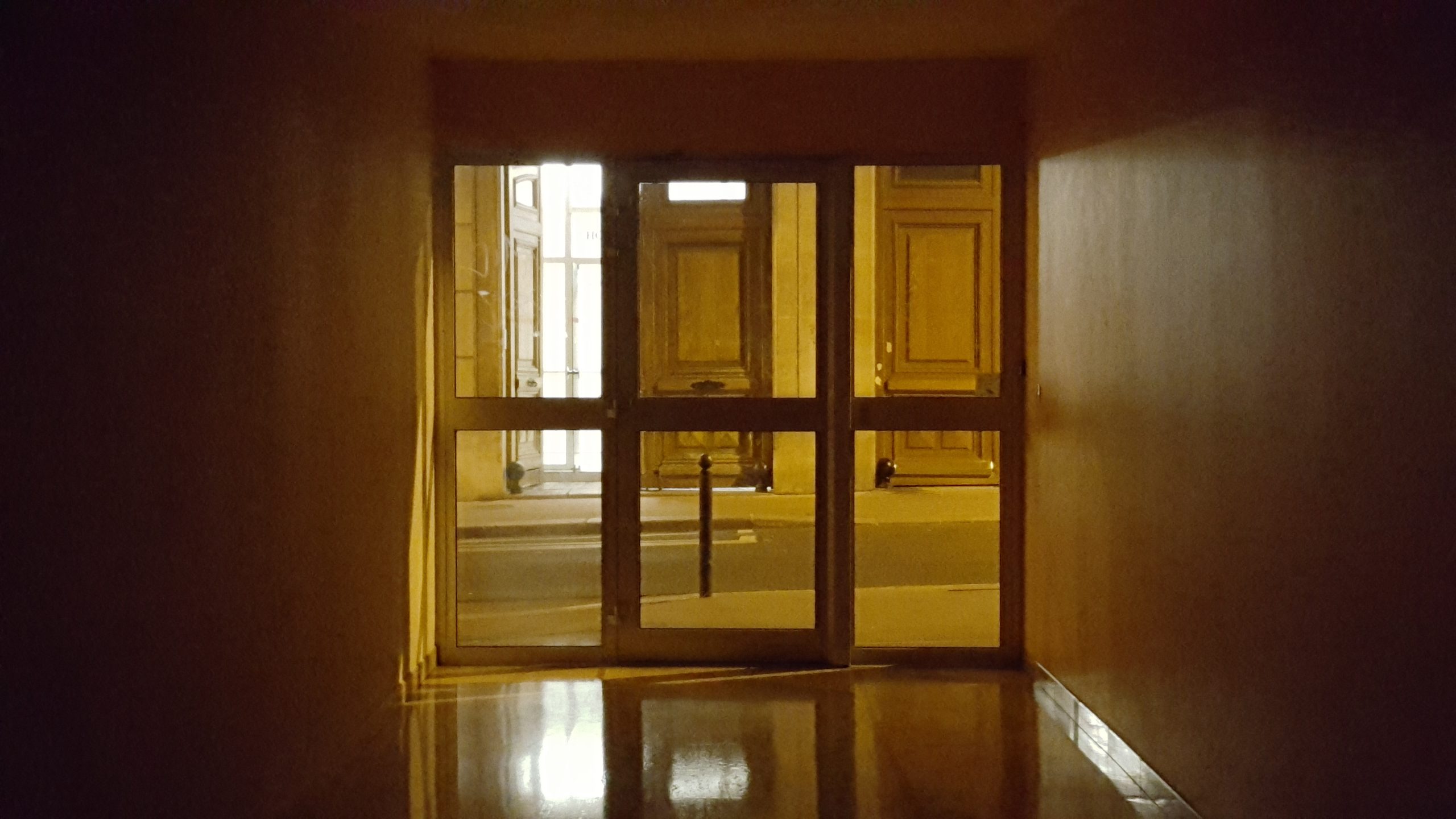 a dark and empty entrance to a building leading out to the streets of Paris